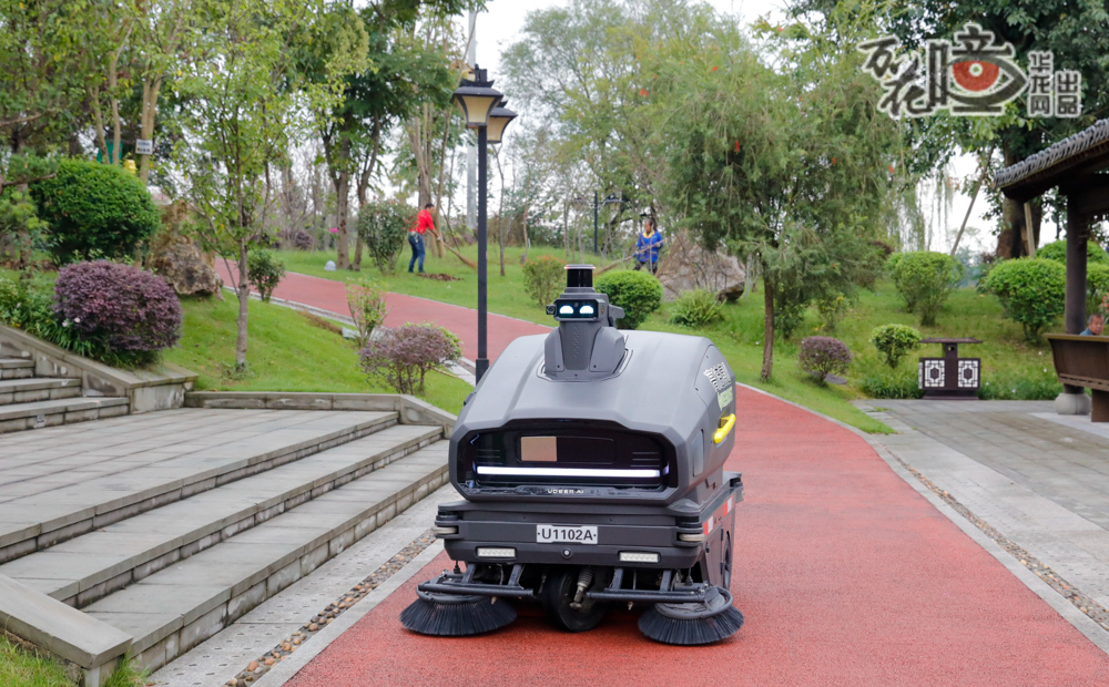 榮昌區玉帶河生態公園內，智能清掃機器人正沿著步道靜靜巡行，而在它身旁的草坪上，環衛工人俯身掃起一片片秋葉。潔凈的公園里，科技的精準與雙手的溫柔交織，共同為市民守護這篇城市中的休閑地
