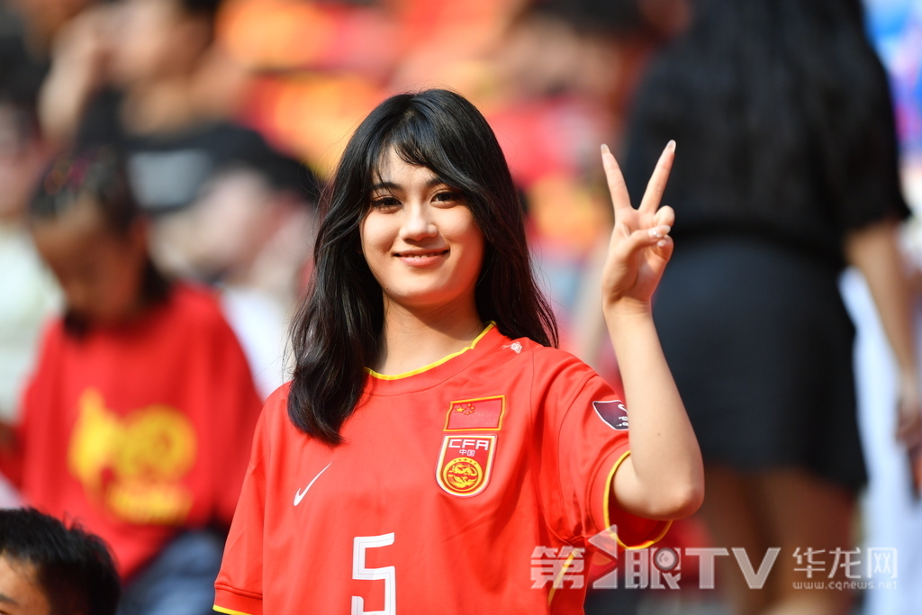 女球迷身着国足 5 号战袍比耶微笑，赛场边的柔美身影藏着炽热支持。第1眼TV-华龙网记者 李一鸣 摄