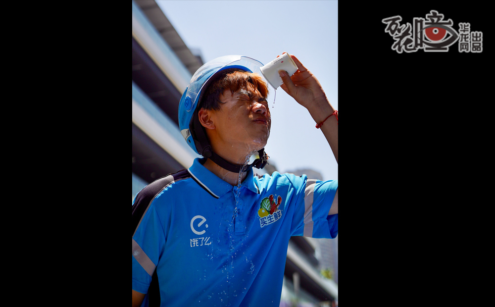 烈日当空，外卖骑手周颖悦站在路边，刚送完一单生鲜，额前的碎发黏在汗湿的脸颊上。他接了一杯冷水，仰头往脸上一浇，以此来降温。