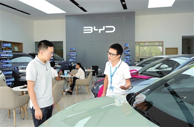 雙桂城區(qū)某汽車(chē)專(zhuān)賣(mài)店，銷(xiāo)售人員（右）在為顧客推介新能源汽車(chē)。