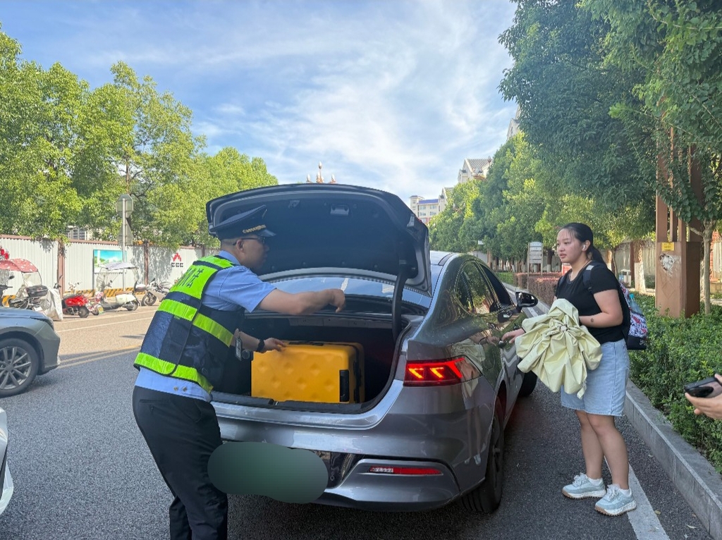 执法人员帮学生搬行李上车。受访者供图