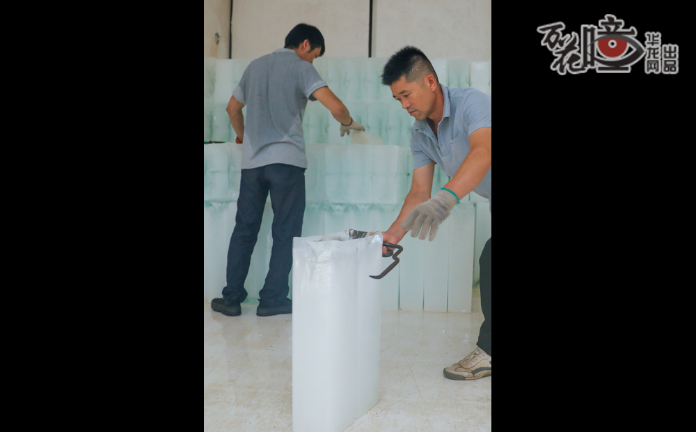 工業(yè)冰制作完成后，工人通過滑槽將冰塊裝上冷鏈運(yùn)輸車。盡管搬運(yùn)的是冰塊，但工人們的后背卻早已被汗水濕透。